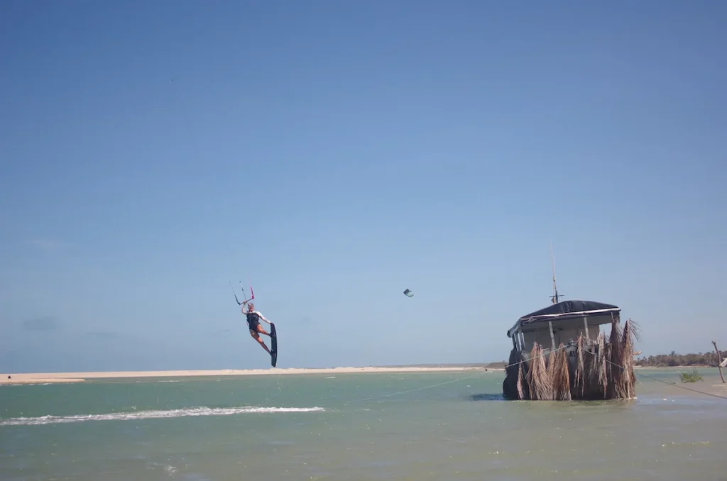 Young woman kiteboarding, joyfully jumping in a Brazilian lagoon, capturing the exhilaration and skill of the sport against the picturesque backdrop of the lagoon.