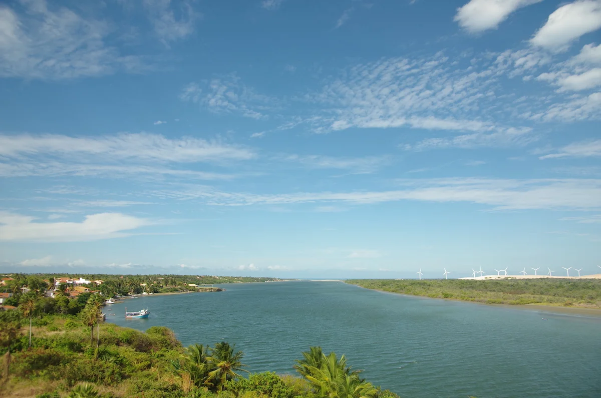 Scenic rivermouth in Brazil framed by dunes and anchored fishing boats