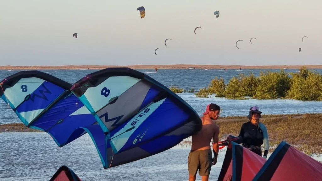 Two kite instructors on a Brazilian beach, each holding a kite, exemplifying the picturesque setting and professional expertise of kiteboarding instruction in this scenic location.
