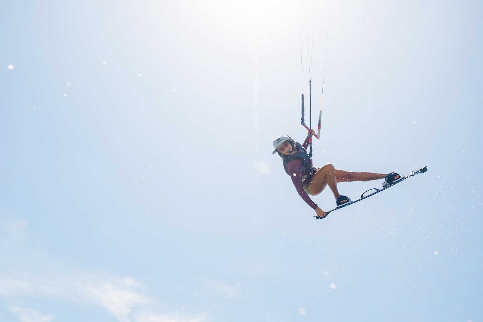 Marie from kitevoyage jumping over the camera while kitesurfing  crossing the sun of Brazil and the blue sky during a kitesurfcamp